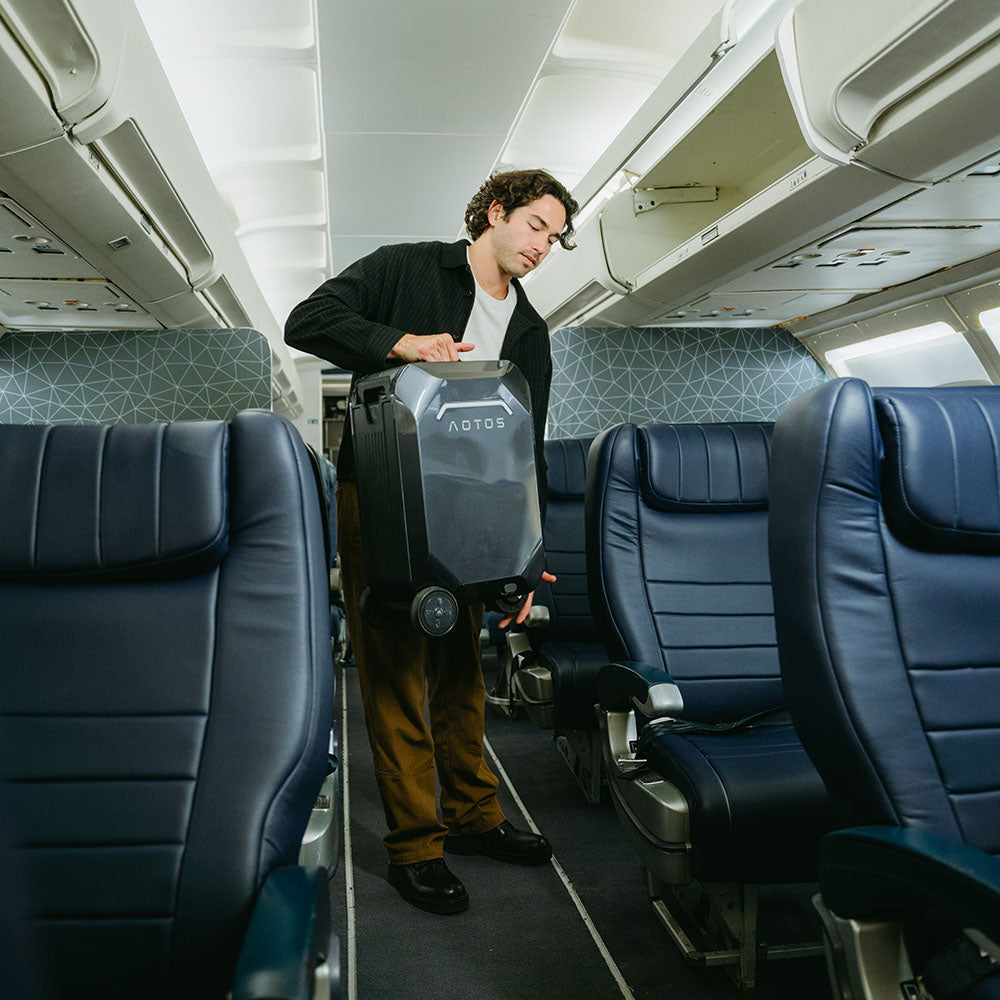 A traveler handles the AOTOS L2 smart electric carry-on suitcase in the aisle of an airplane.