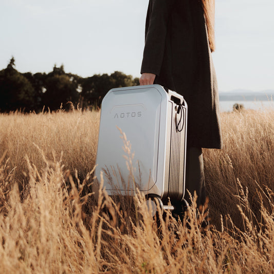raveler carrying the sleek AOTOS L2 suitcase through a golden field, showcasing its modern hard-shell design and portable style.