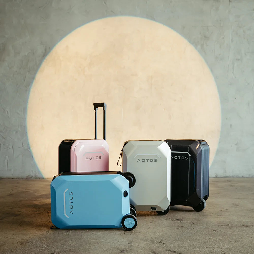Studio lineup of AOTOS L2 smart rideable suitcases in blue, blush pink, ivory and midnight black, spotlighting stylish color options