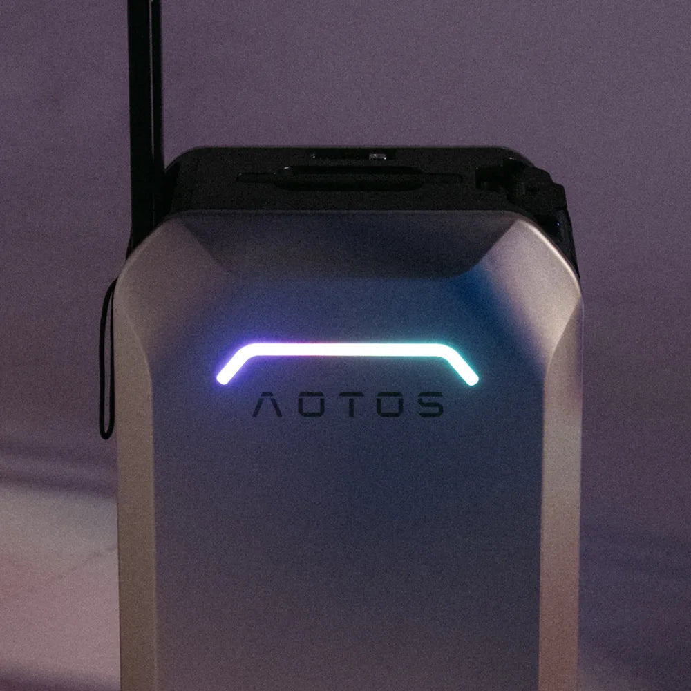 AOTOS L2 electric ride-on luggage in low-light setting with multicolor LED front logo glowing for nighttime visibility